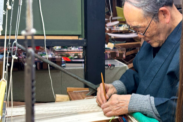 Artisan Kikuo Hirano weaving tsuzure-ori by hand using his fingernails
