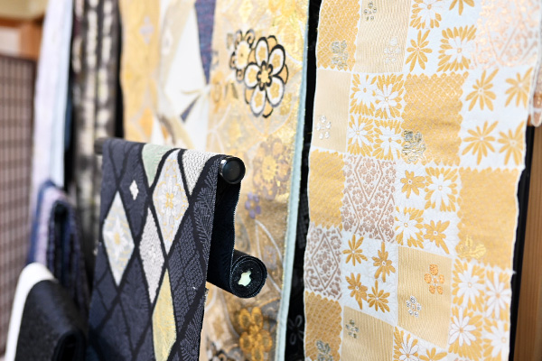 Exquisite Nishijin-ori obi textiles with gold and silver threads displayed in a studio