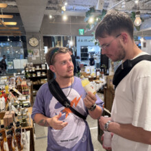Two visitors chatting inside a Kyoto specialty shop lined with shelves of local products